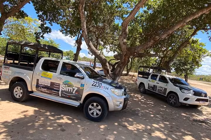 Shared 4x4 shuttle vehicles for Fortaleza to Jericoacoara transfer, parked under trees during stop