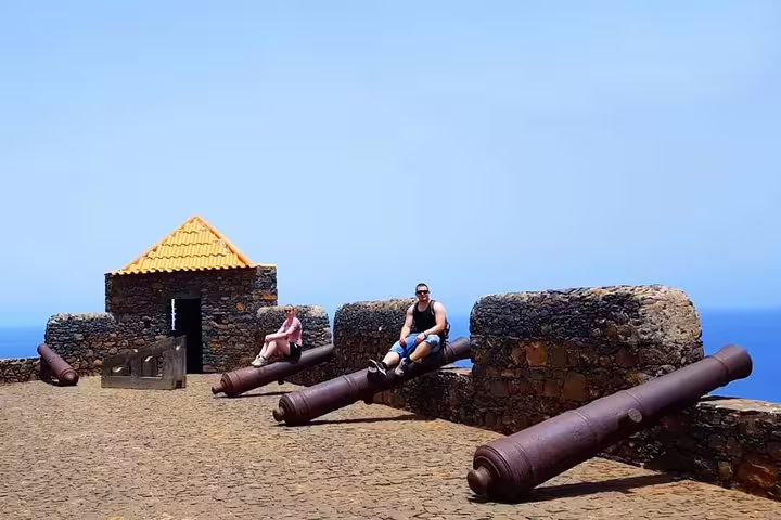 Visitors sitting on cannons at Fortaleza Real de São Filipe, Cidade Velha on guided historic tour from Praia