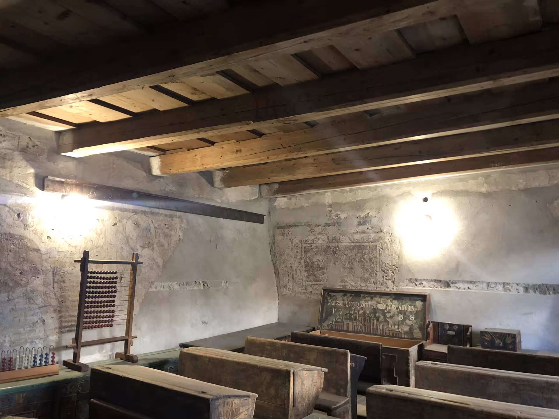 Historic classroom inside a Transylvanian fortified church with wooden benches, abacus, and stone walls