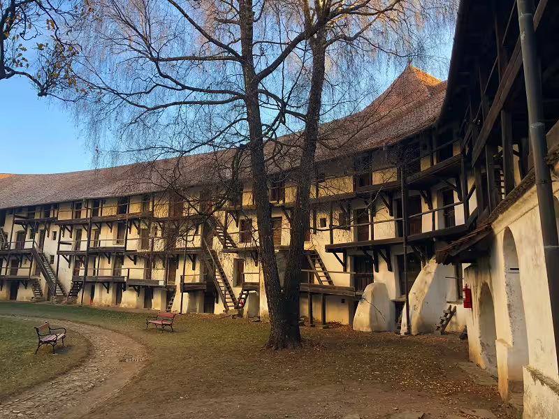 Interior courtyard of a medieval fortified church with timber-framed galleries and bare trees in Transylvania