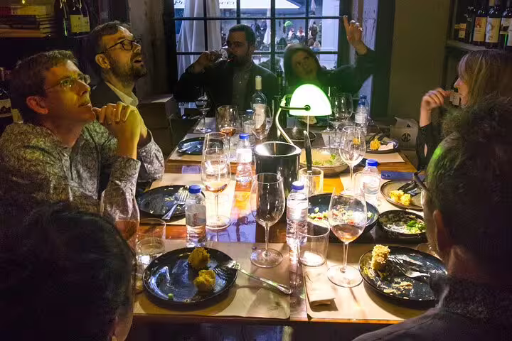 Group enjoying a cozy fortified wine tasting experience with a producer, featuring diverse wines and engaging discussions.