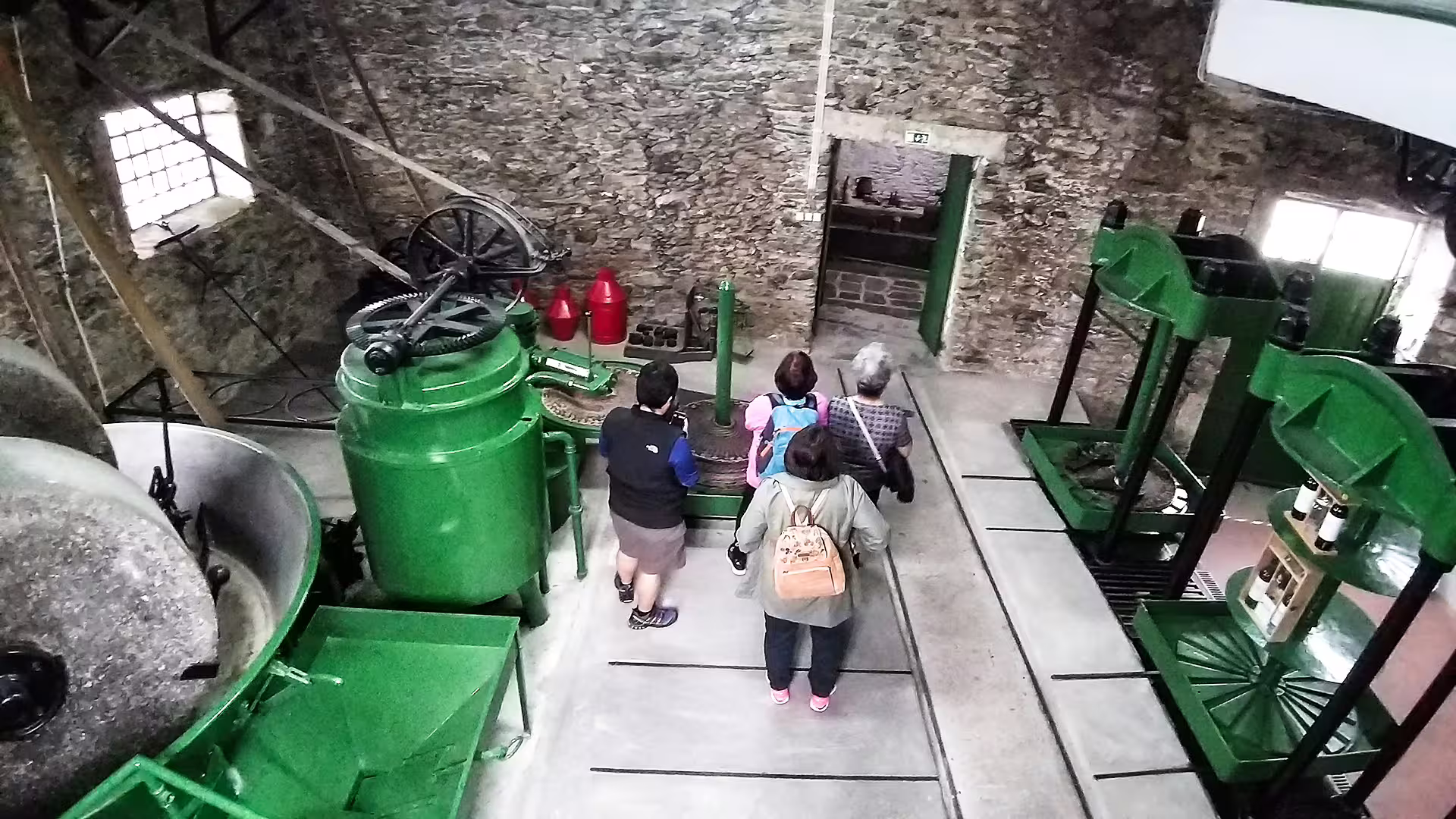 Visitors explore traditional olive oil machinery during the Foz Côa and Douro private tour, showcasing historic production methods.