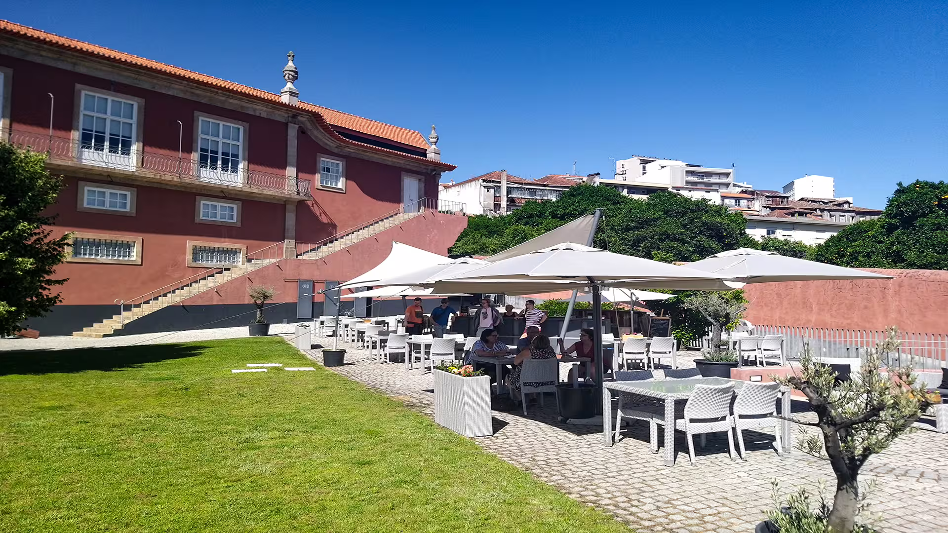 Outdoor patio dining area in Vila Nova de Foz Côa with umbrellas and lush greenery, perfect for enjoying Douro wines.