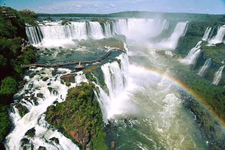 Aerial view of Iguazu Falls with a vibrant rainbow, highlighting the stunning natural beauty on a Foz do Iguaçu tour.