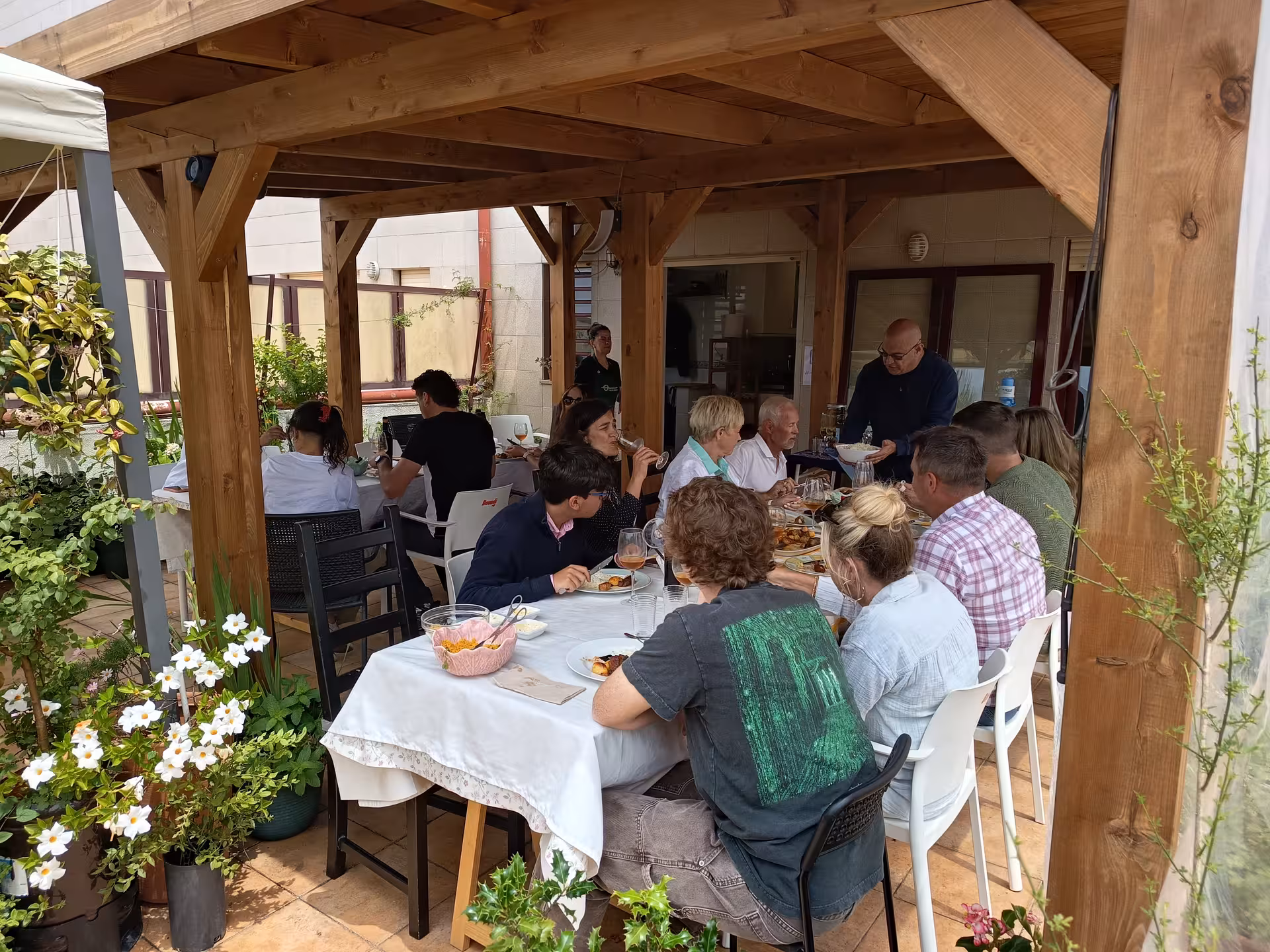 Guests enjoying a delicious meal under a wooden pergola during the Francesinha cooking class in Porto.
