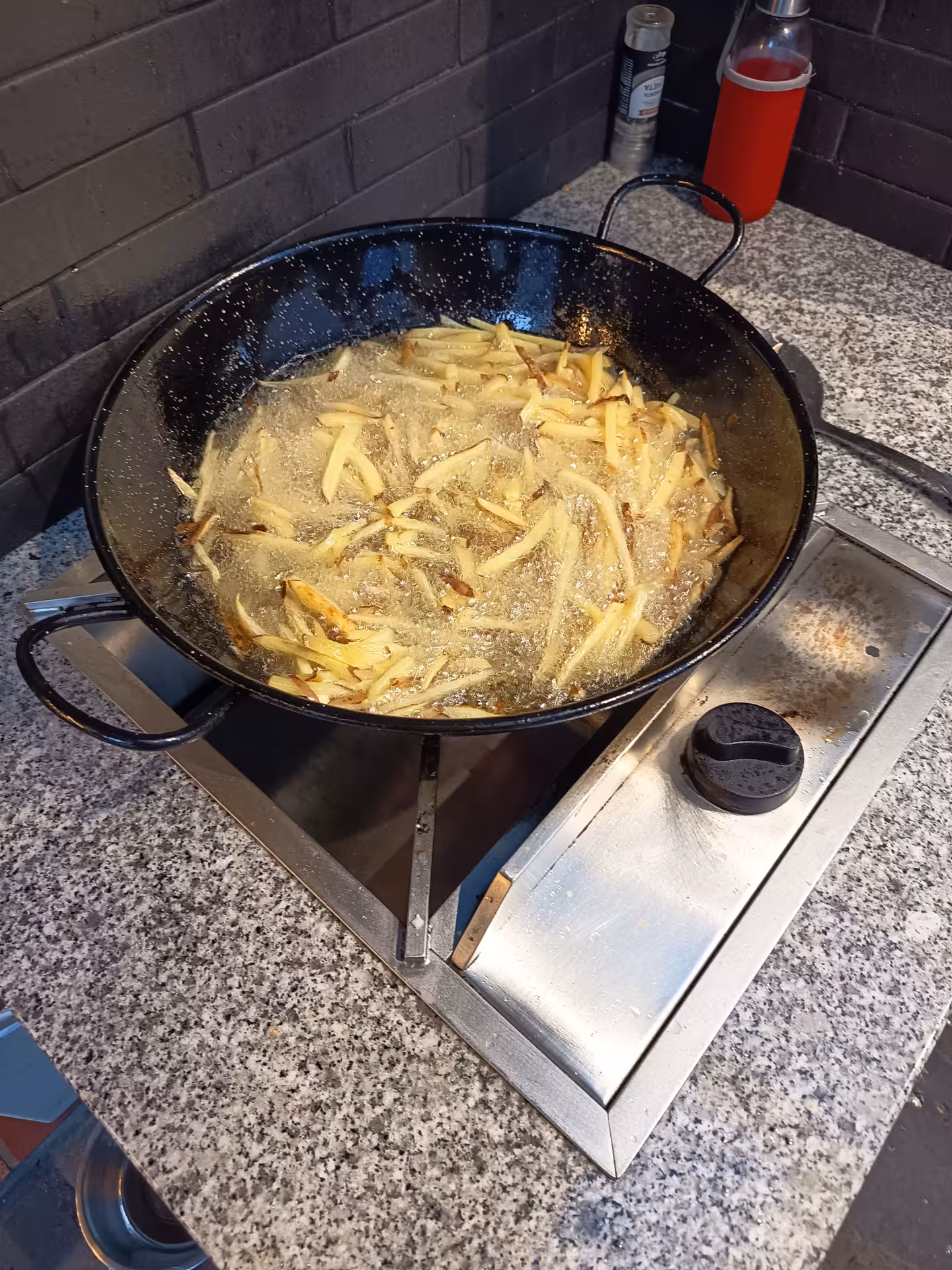 Golden French fries sizzling in a pan, part of the Francesinha cooking experience in Porto.
