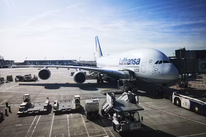 Lufthansa Airbus A380 parked at Frankfurt Airport gate with ground crew vehicles