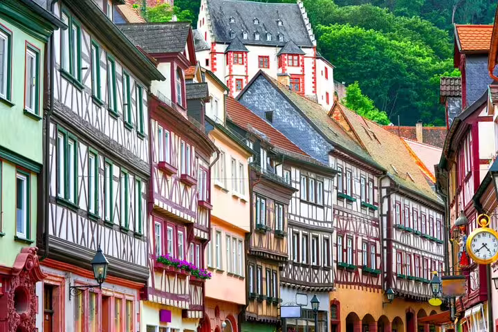 Colorful half-timbered buildings lining a historic street in Frankfurt Old Town with a hilltop castle behind