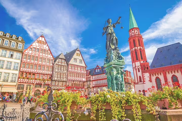 Römerberg square in Frankfurt Old Town with half-timbered buildings, Lady Justice statue, and Kaiserdom church tower