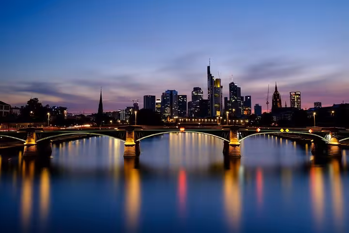 Frankfurt skyline at dusk with illuminated bridge reflecting on the Main River