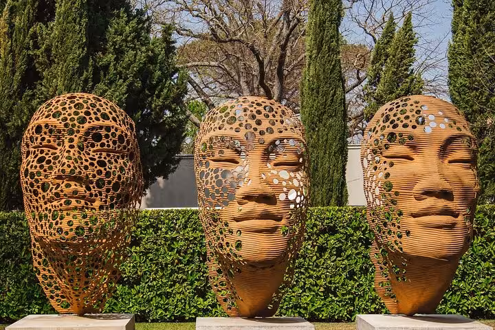 Discover the artistic allure of Franschhoek with intricate face sculptures set against lush greenery on the Blue Line tour.