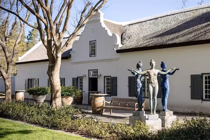 Historic Cape Dutch architecture with modern art sculptures in Franschhoek, featured in Cape Town day tours.