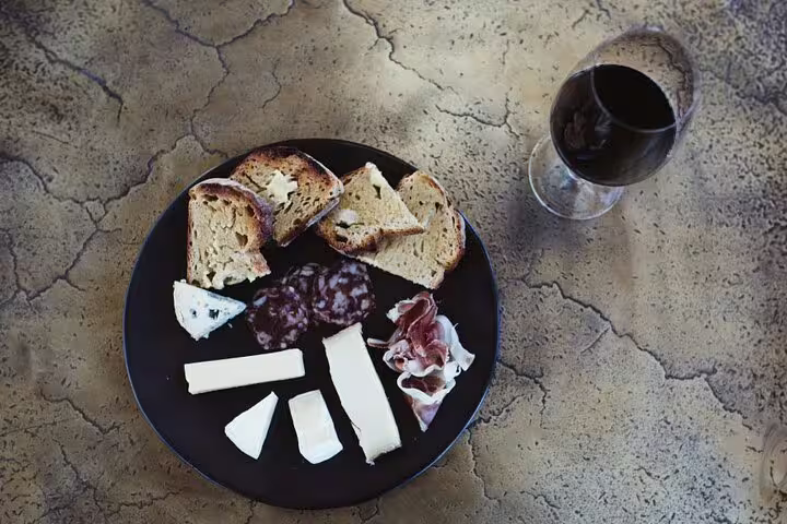 Gourmet cheese and charcuterie plate with red wine on the Franschhoek Tram, ideal for wine lovers in South Africa.