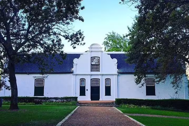 Charming Cape Dutch architecture at a historic winery on the Franschhoek wine tram tour.