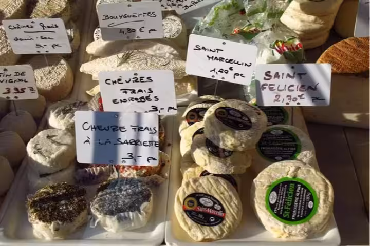 Assortment of artisanal French cheeses on display at a market in Nice, perfect for an evening food and wine tour.