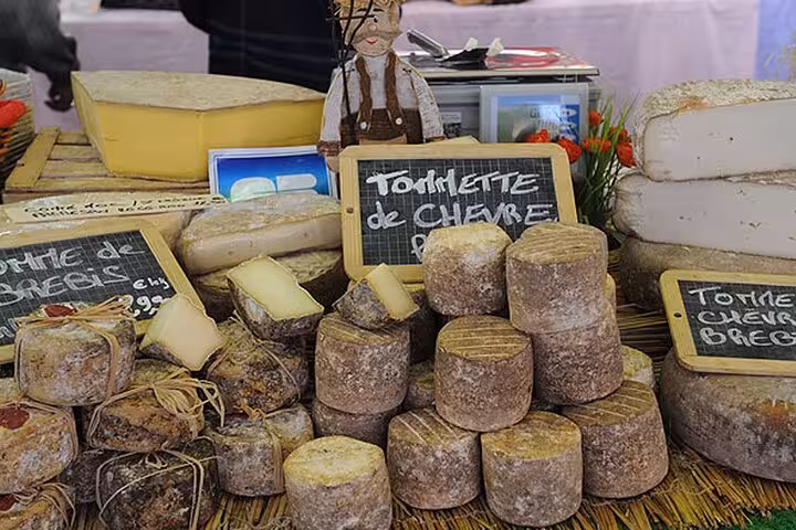 Tomme de chèvre and brebis cheeses displayed at a French Riviera market stall in Cannes