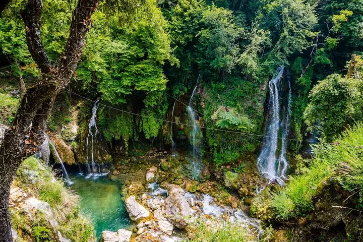 Multiple cascading waterfalls flowing into turquoise pools surrounded by lush green forest in French Riviera countryside
