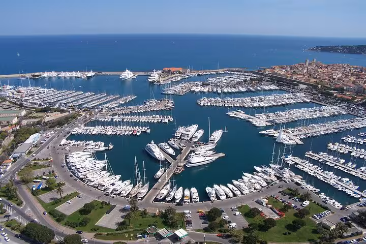 Aerial view of a bustling French Riviera marina packed with luxury yachts and sailboats near a coastal town