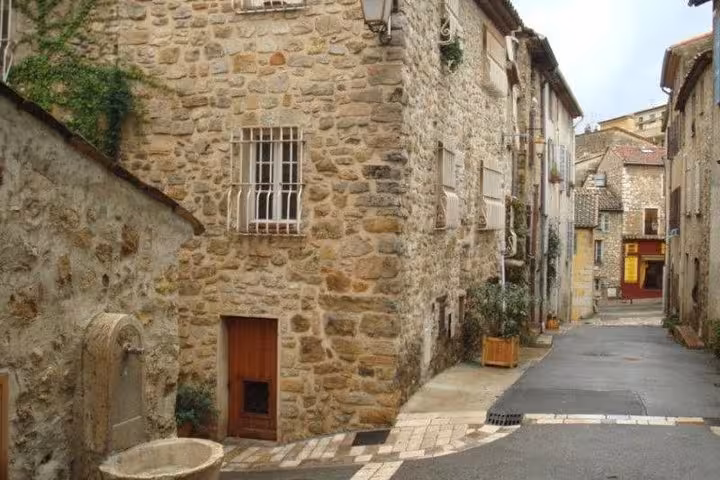 Narrow stone-paved street lined with medieval limestone buildings in a French Riviera countryside village