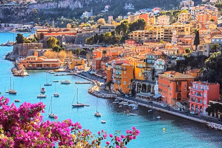 Colorful waterfront buildings and sailboats in a turquoise bay on the French Riviera