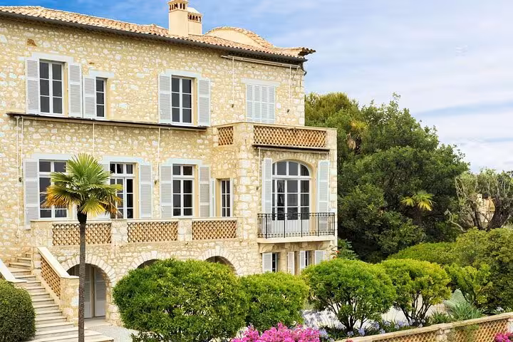 Elegant stone villa on the French Riviera surrounded by lush gardens and scenic beauty.