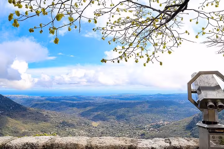 Scenic view from a French Riviera vantage point with a telescope overlooking lush valleys and distant sea.