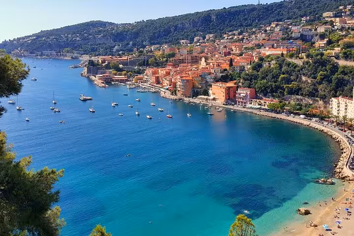 Aerial view of Villefranche-sur-Mer bay with turquoise water, sailboats, and colorful buildings on French Riviera