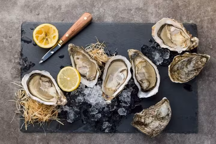 Fresh oysters on a slate platter with lemon and ice, highlight of the exclusive Riviera seafood tasting tour.