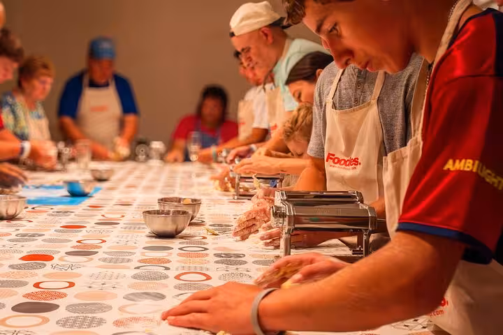 Group of people crafting fresh pasta in a hands-on Barcelona workshop, engaging in a unique culinary experience.