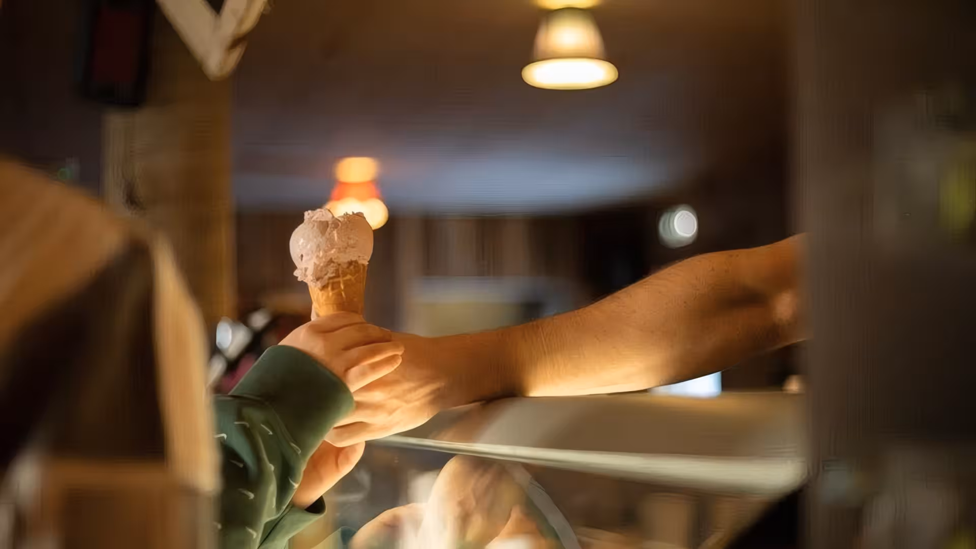 Server handing an ice cream cone to a visitor at Fridheimar Farm in Iceland