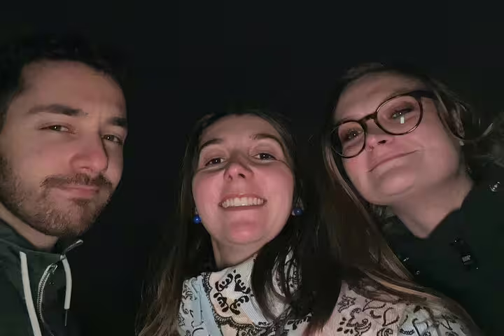 Three friends smiling together at night during Brussels beer walking tour in Old Town