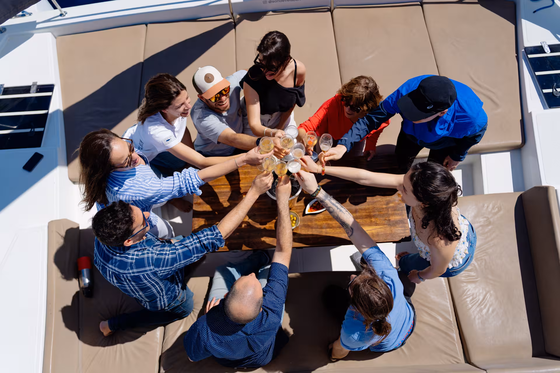 Friends clinking cava on Bali 4.1 deck during 3-hour private luxury catamaran Barcelona sailing experience