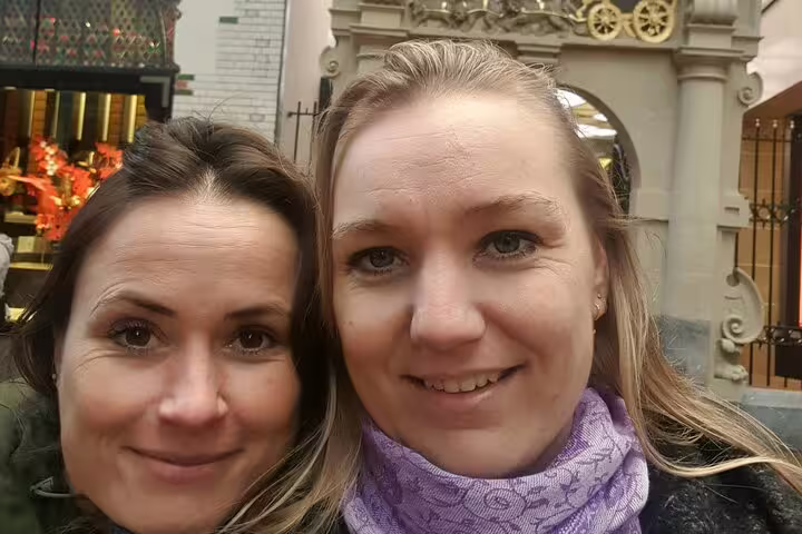Two smiling women posing together in front of an ornate Amsterdam building entrance