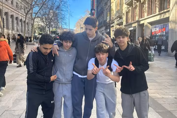 Group of five young friends posing together on a busy Barcelona street during a walking tour