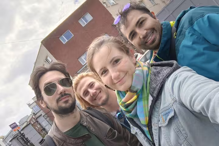 Four smiling friends posing together for a selfie outdoors in a city street