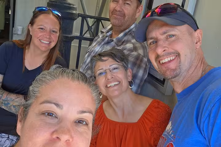 Group of five smiling friends taking a selfie together on a New Orleans French Quarter tour