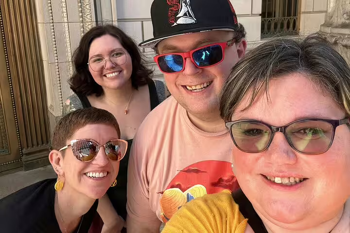 Group of four smiling friends taking a selfie during a Portland walking tour outside a historic building