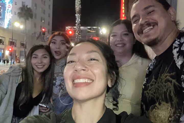 Group of friends smiling at night on Hollywood Boulevard during a ghost hunt walking tour