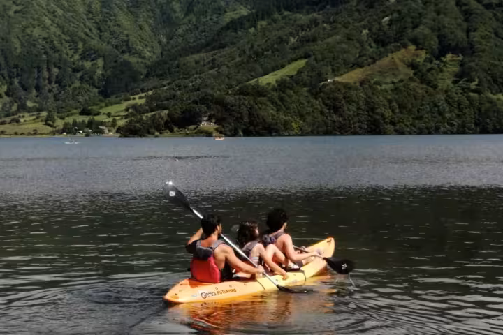 Friends kayaking on the tranquil Sete Cidades crater lake, enjoying a half-day Azores adventure with lush volcanic hills around