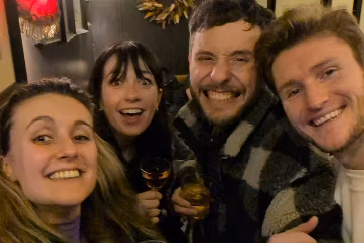 Four friends smiling and holding drinks at a Dublin pub during a self-guided tour adventure