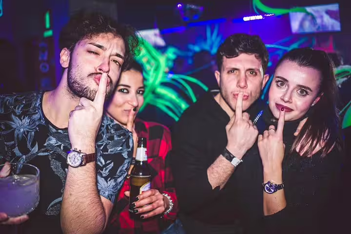 Group of friends enjoying lively nightlife at a Madrid pubcrawl, posing playfully with drinks in hand.