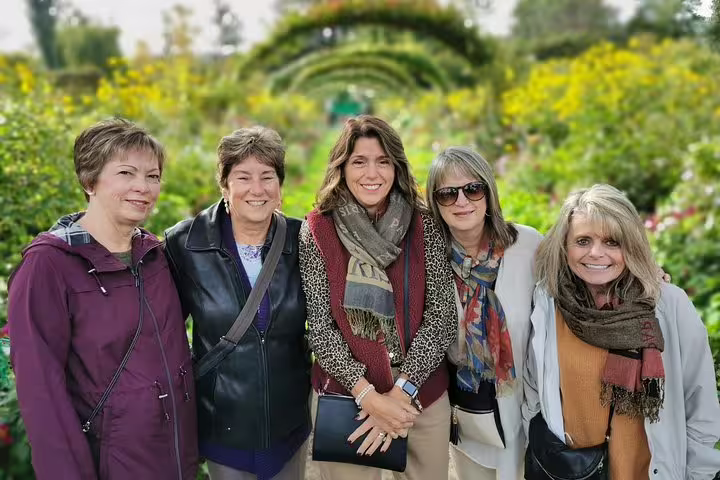 Friends posing in Monet’s Giverny gardens under flower arches on a private Giverny and Auvers-sur-Oise tour