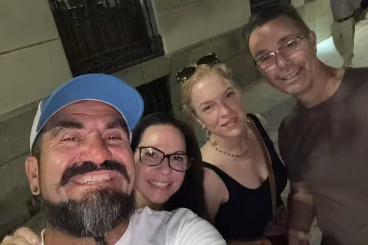 Four smiling friends posing together at night on a Madrid street during a ghost walking tour