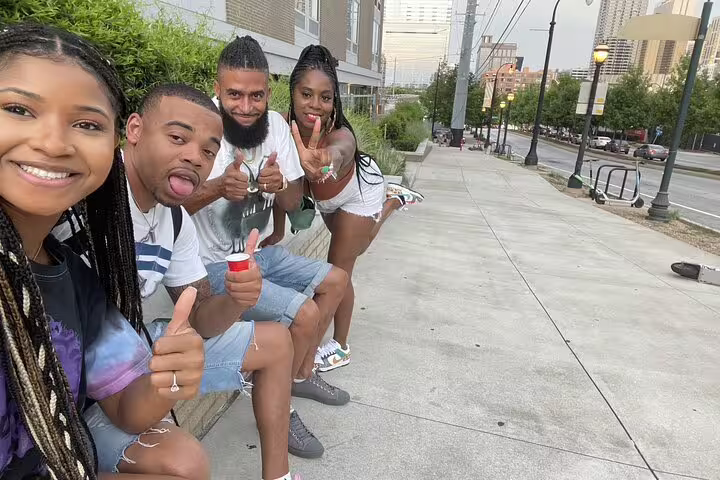 Four friends posing and smiling on a Downtown Atlanta sidewalk during a walking tour