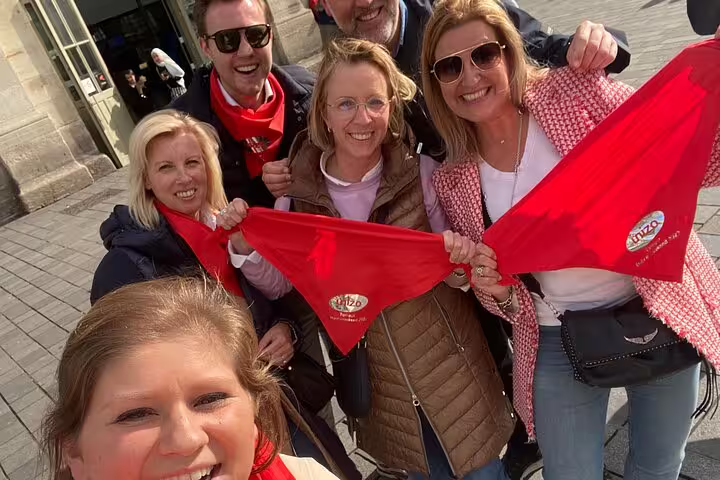 Friends holding red clues during an e-scavenger hunt in Montpellier, France, exploring landmarks at their own pace