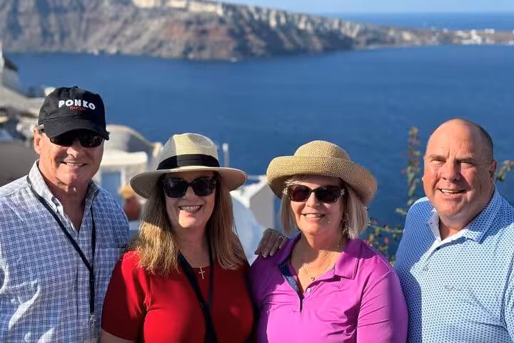 Friends posing on Santorini caldera viewpoint during a personalized private tour with Aegean Sea backdrop