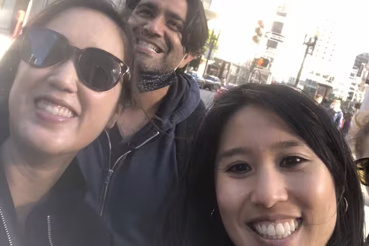 Three smiling friends on a self-guided walking tour in San Francisco city streets