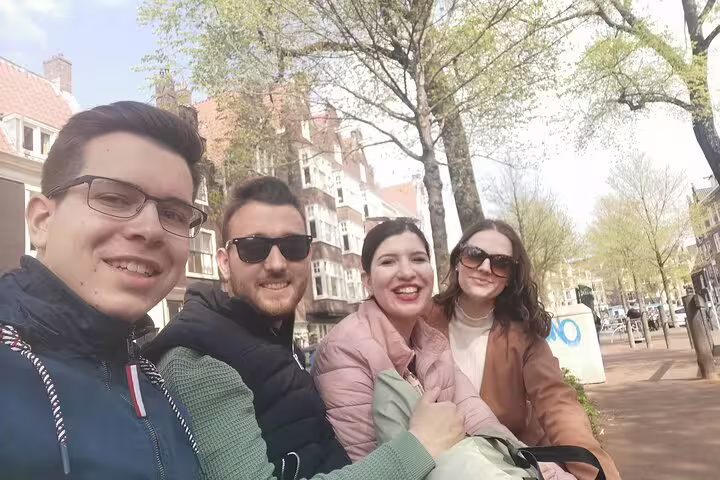 Four smiling friends taking a selfie on a sunny street in Amsterdam's Jordaan neighborhood