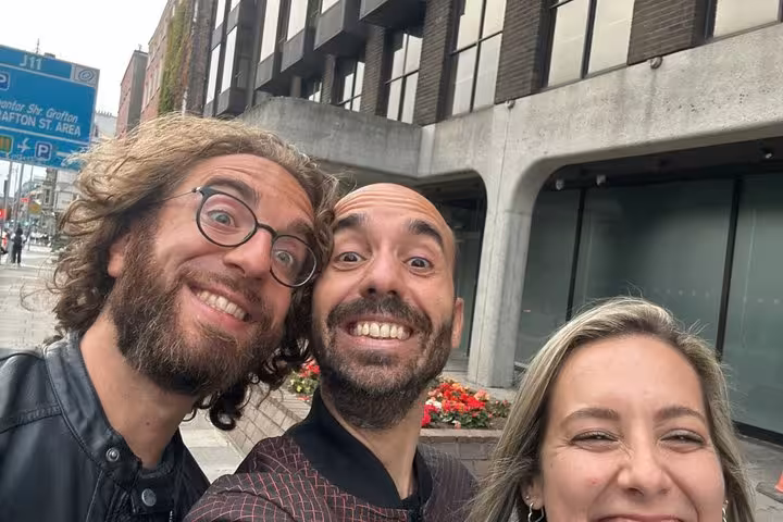 Three smiling friends taking a selfie on a Dublin city street during a pub tour adventure