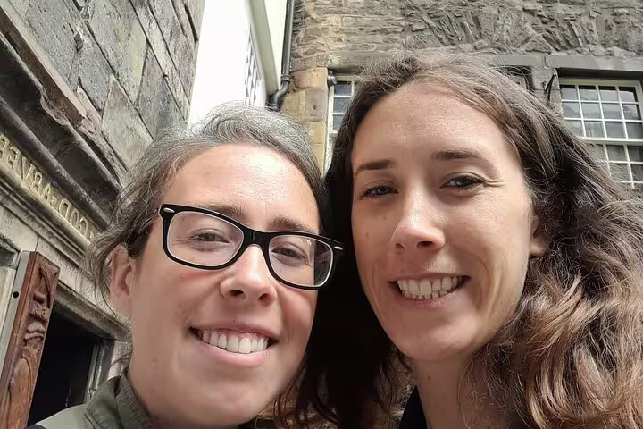 Two smiling women taking a selfie on a gothic stone alley in Edinburgh